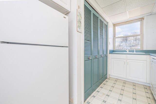 10989 Seminole Shore Dr, Huntsville, OH 43324 - kitchen featuring freestanding refrigerator, a sink, a drop ceiling, white cabinetry, and light floors