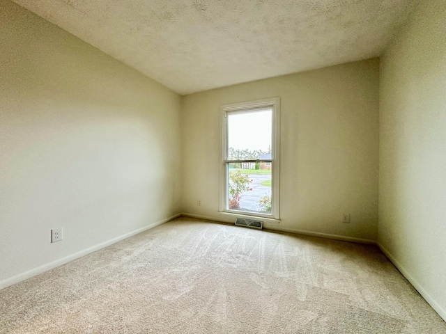 carpeted spare room featuring visible vents, a textured ceiling, and baseboards