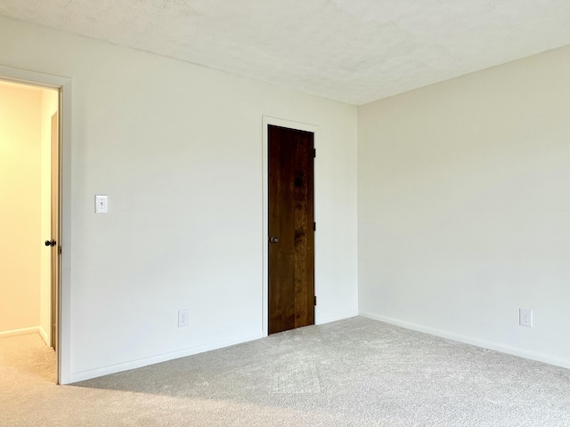 carpeted empty room featuring a textured ceiling and baseboards