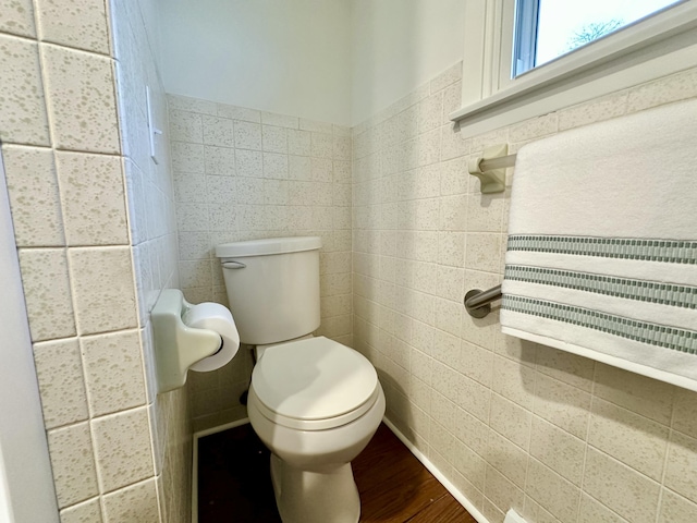 half bathroom with toilet, tile walls, and wood finished floors