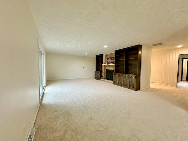 unfurnished living room featuring a textured ceiling, a fireplace, carpet flooring, and baseboards