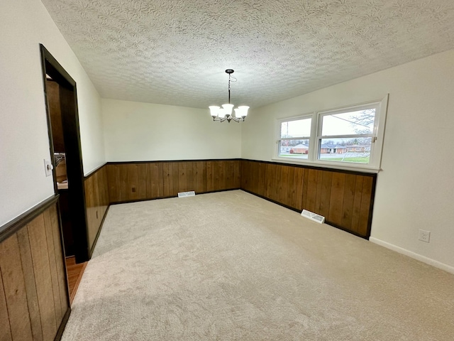 spare room with wooden walls, visible vents, and wainscoting