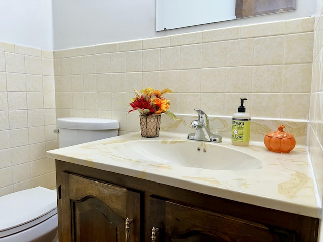 half bathroom with tile walls, toilet, and vanity