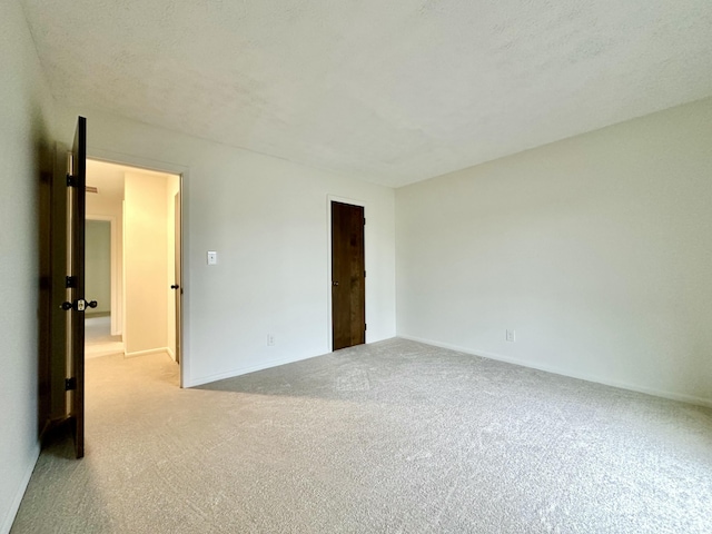 carpeted empty room with a textured ceiling and baseboards