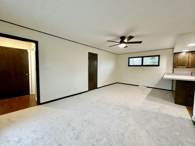 unfurnished living room featuring ceiling fan, carpet flooring, and baseboards