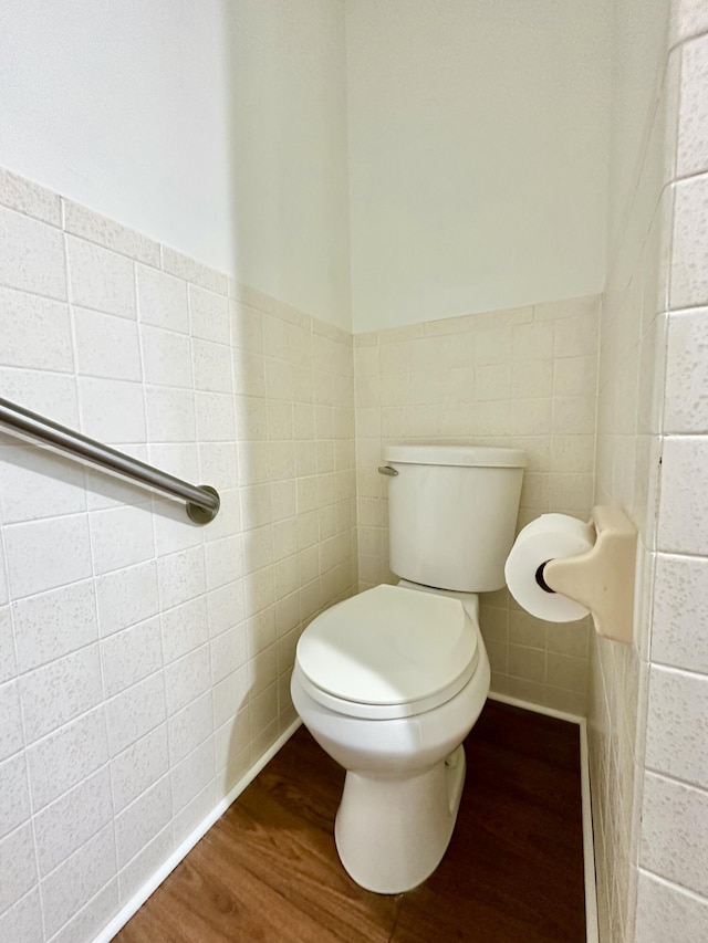 bathroom featuring toilet, tile walls, wood finished floors, and wainscoting