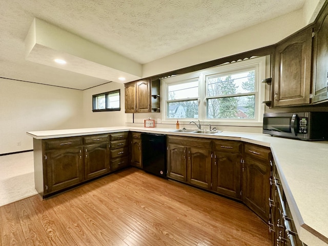 kitchen with dishwasher, stainless steel microwave, a peninsula, light wood-style floors, and a sink