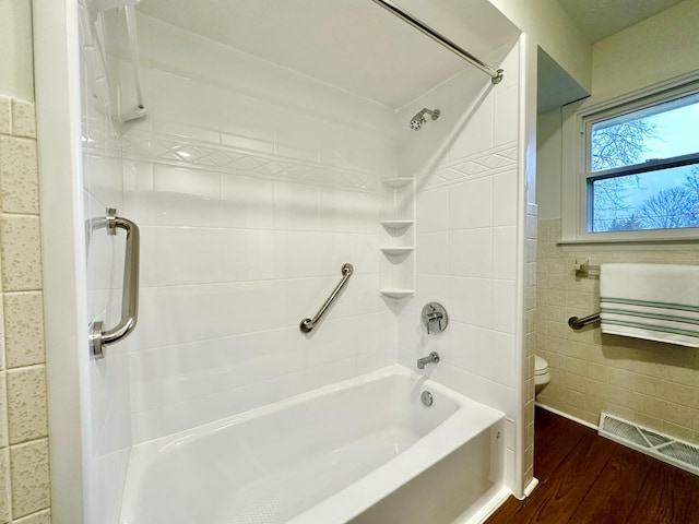 full bathroom featuring visible vents, toilet, wood finished floors, bathtub / shower combination, and tile walls