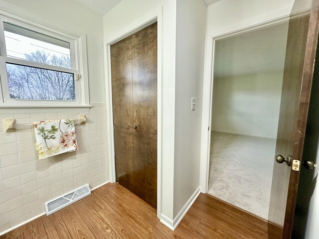 bathroom featuring wainscoting, wood finished floors, visible vents, and tile walls