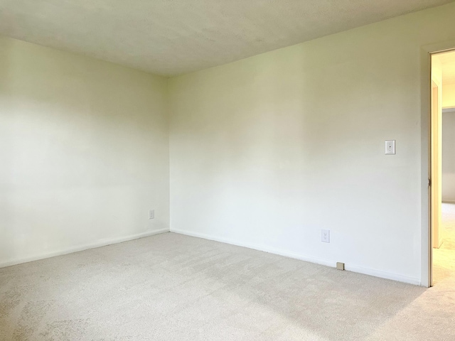 carpeted empty room featuring baseboards