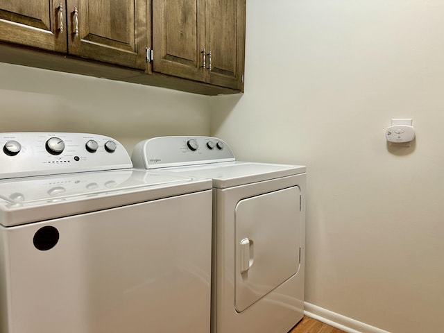 laundry area with washer and dryer, cabinet space, light wood finished floors, and baseboards