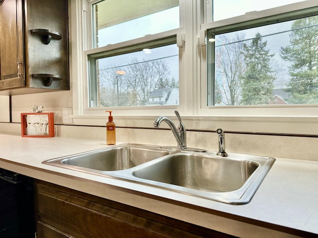 kitchen featuring dark brown cabinetry, light countertops, a sink, and dishwasher