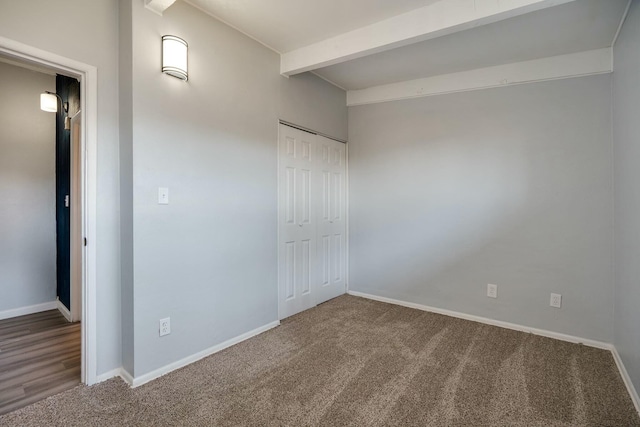 unfurnished bedroom with beamed ceiling, carpet, baseboards, and a closet