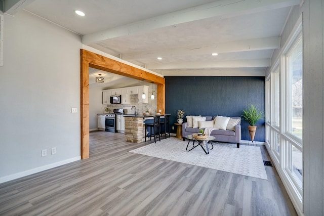 living room with visible vents, lofted ceiling with beams, wood finished floors, recessed lighting, and baseboards