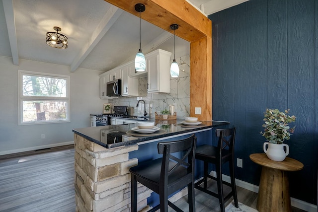 kitchen featuring a sink, backsplash, dark countertops, white cabinetry, and stainless steel appliances