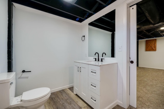 bathroom featuring toilet, vanity, baseboards, and wood finished floors