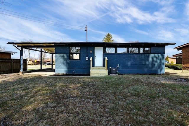 view of front of home featuring a front lawn, an attached carport, brick siding, and fence