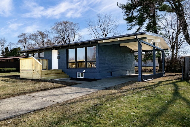 view of front of house featuring a front yard, brick siding, and driveway