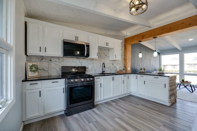 kitchen with dark countertops, gas stove, beam ceiling, a sink, and stainless steel microwave