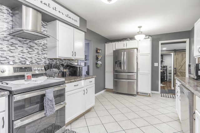 kitchen featuring white cabinetry, stainless steel appliances, a barn door, and wall chimney range hood