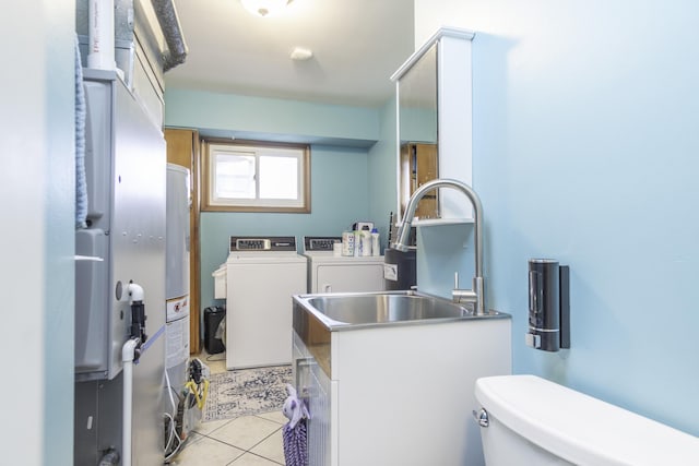 laundry room featuring light tile patterned flooring, washing machine and clothes dryer, and sink