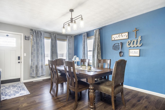 dining area with dark hardwood / wood-style floors, a notable chandelier, and a textured ceiling