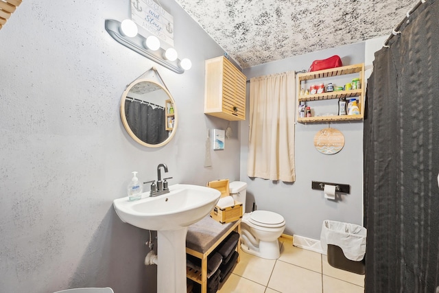 bathroom with tile patterned flooring, toilet, baseboards, and a sink