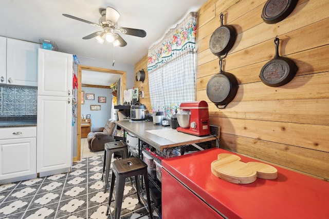 office space with tile patterned floors, wooden walls, and ceiling fan