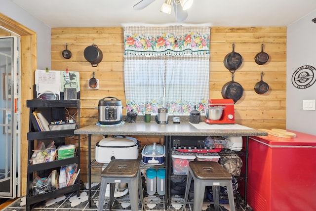 kitchen featuring wood walls and a ceiling fan