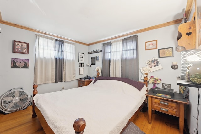 bedroom featuring ornamental molding and wood finished floors