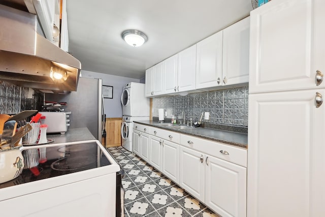 kitchen featuring ventilation hood, light floors, stacked washing maching and dryer, electric stove, and a sink