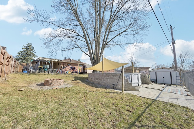 view of yard featuring an outbuilding, an outdoor fire pit, a fenced backyard, a storage unit, and a patio area