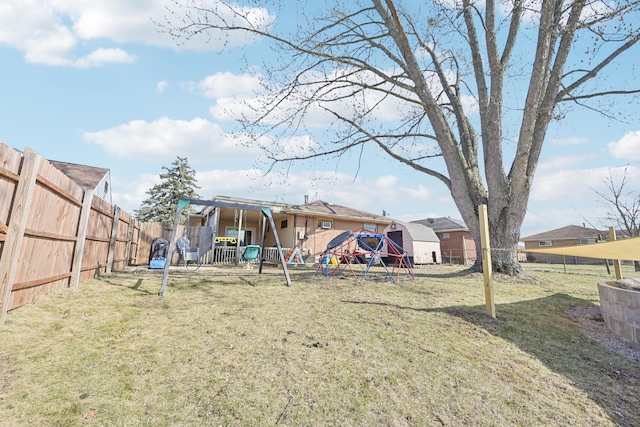 view of yard featuring an outbuilding, a storage unit, a playground, and a fenced backyard