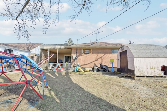 rear view of property with a storage unit, a wall unit AC, a playground, an outdoor structure, and brick siding