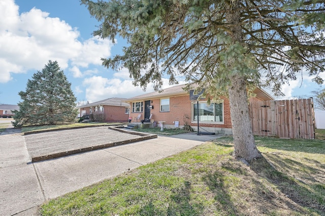 ranch-style home with brick siding, a front lawn, and fence