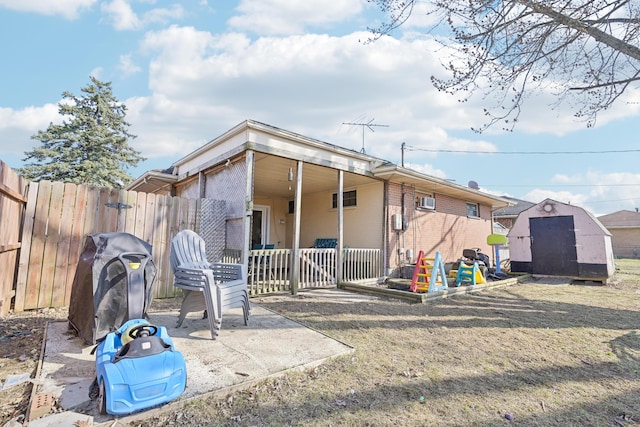 back of property with a patio, fence, brick siding, and an outbuilding