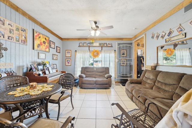 living area featuring a textured ceiling, light tile patterned flooring, visible vents, and ceiling fan