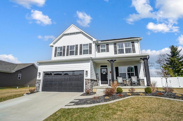 view of front of home featuring fence, driveway, a porch, an attached garage, and stone siding