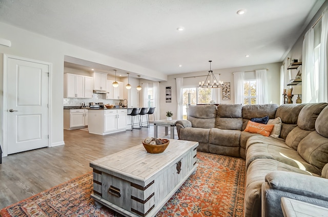 living room featuring recessed lighting, an inviting chandelier, and light wood-style flooring