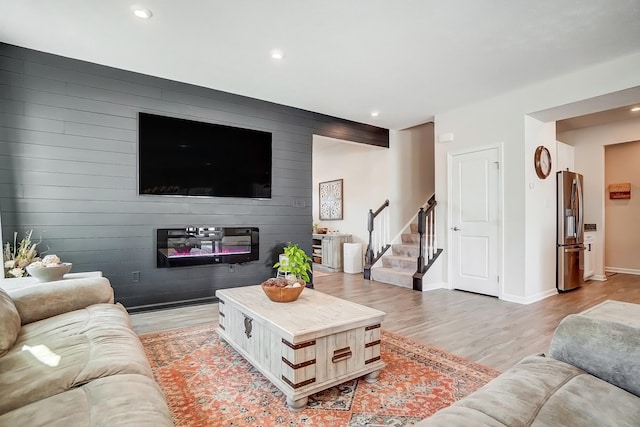 living area with baseboards, recessed lighting, stairs, light wood-style floors, and an accent wall