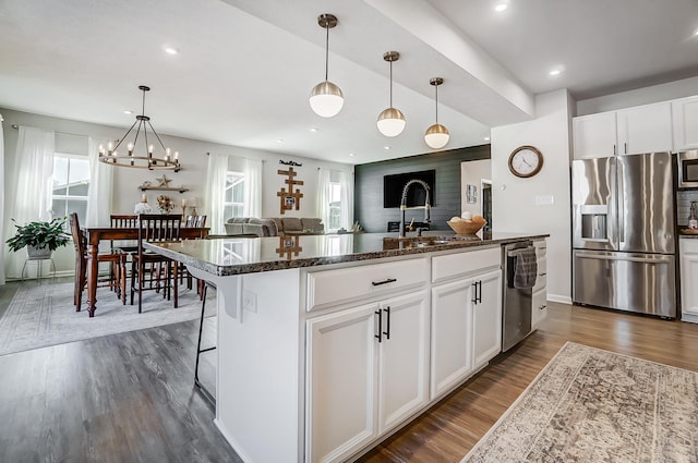 kitchen with dark wood finished floors, dark stone counters, a sink, white cabinets, and appliances with stainless steel finishes