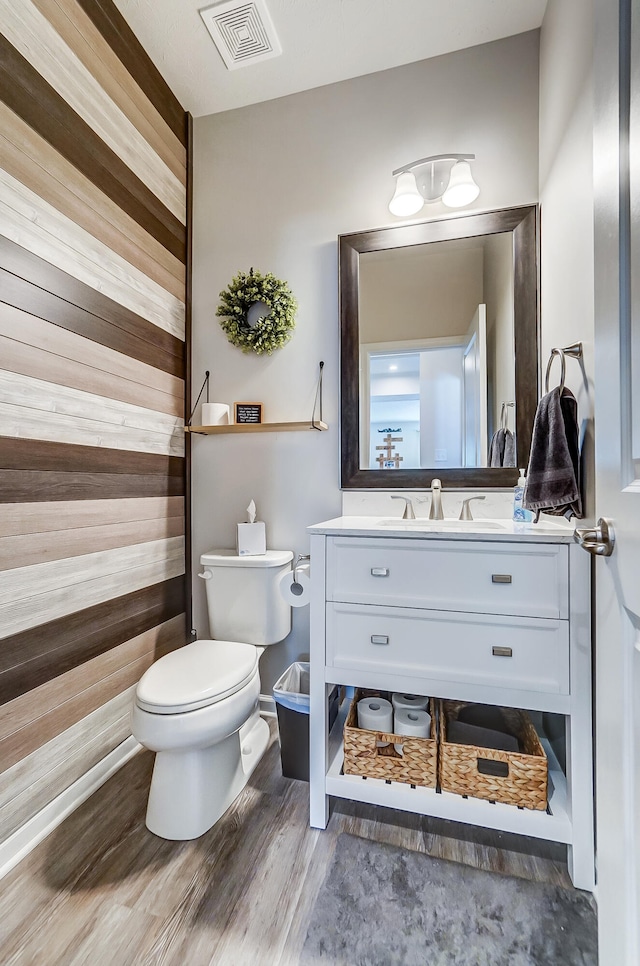 bathroom featuring visible vents, toilet, wood finished floors, and vanity