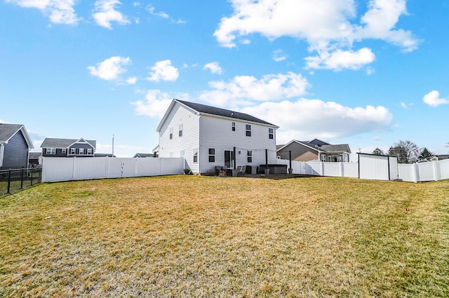 rear view of house featuring a lawn and a fenced backyard