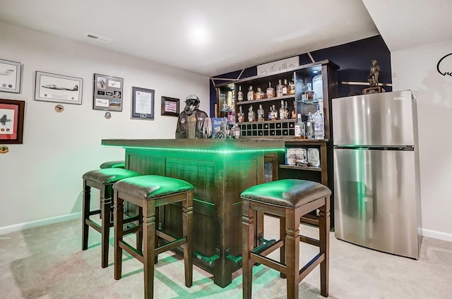 bar with visible vents, carpet, a dry bar, and freestanding refrigerator