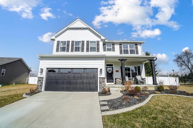 craftsman-style home featuring board and batten siding, a front lawn, covered porch, stone siding, and driveway