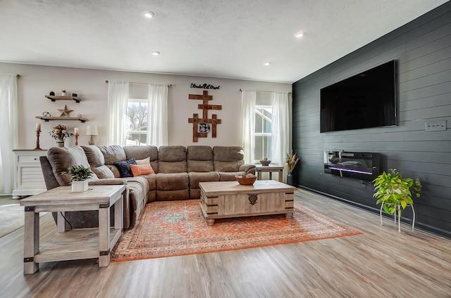 living room featuring wooden walls, recessed lighting, wood finished floors, and a textured ceiling