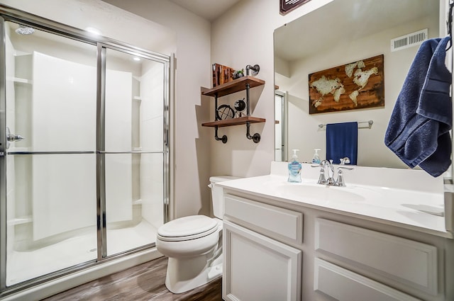 bathroom with visible vents, toilet, a stall shower, wood finished floors, and vanity