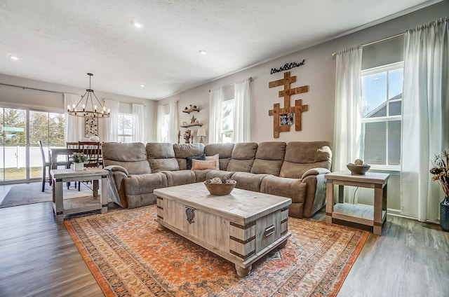 living area with a healthy amount of sunlight, an inviting chandelier, and wood finished floors