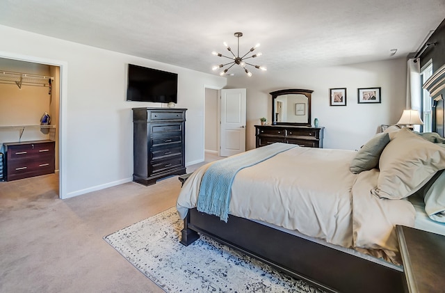 bedroom with a walk in closet, light colored carpet, baseboards, and a chandelier