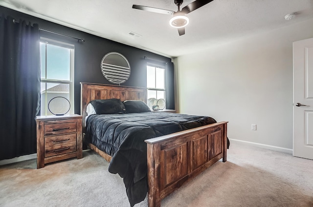 bedroom with ceiling fan, light colored carpet, visible vents, and baseboards